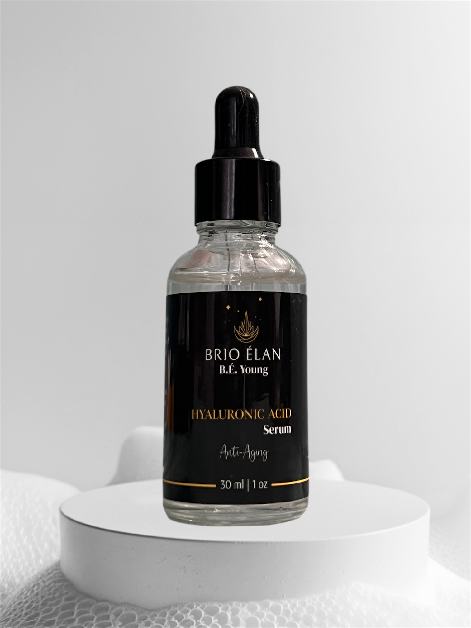 A clear glass bottle with a dropper containing Hyaluronic Acid Facial Serum, labeled BRIO ÉLAN. The bottle is presented on a white platform with a white background.