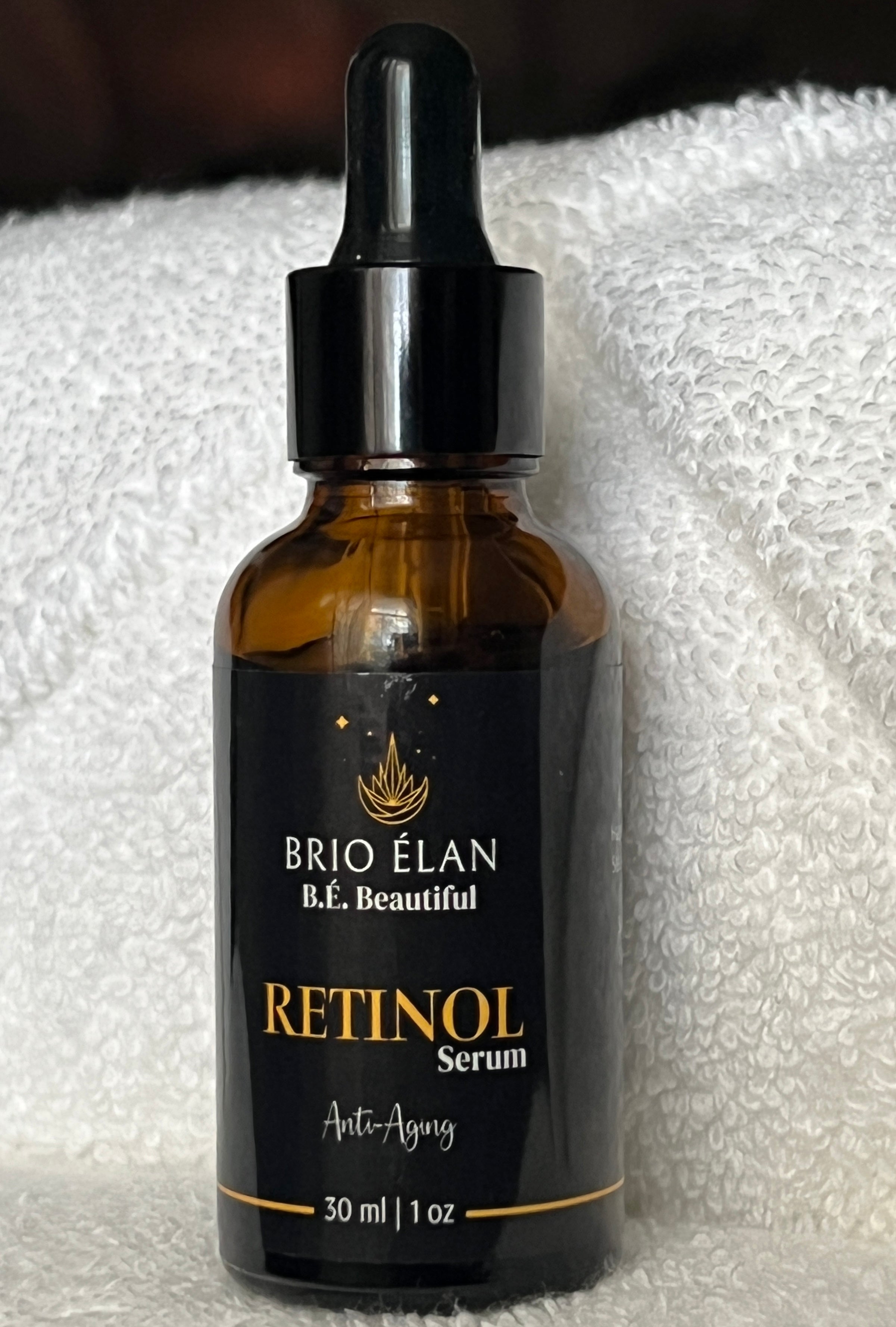 A glass dropper bottle of BRIO ÉLAN Retinol serum on a white terry cloth towel.